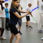 Teilnehmer inszenieren ein filmisches Schwertduell mit Lichtschwert und Degen beim Kinderworkshop Epische Film-Duelle in Duisburg