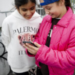 Kinder und Jugendliche betrachten gemeinsam ihre entstandenen Fotos auf dem Smartphone im Workshop Fake It Dinslaken.